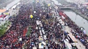 তারেক রহমানের স্বদেশ প্রত্যাবর্তন জনসমুদ্রে পরিণত ৩০০ ফিট সড়ক বিএনপির ভারপ্রাপ্ত চেয়ারম্যান তারেক রহমানকে স্বাগত জানাতে রাজধানীর পূর্বাচলের ৩৬ জুলাই এক্সপ্রেসওয়ে (তিনশ ফিট সড়ক) জনসমুদ্রে পরিণত হয়েছে। গতকাল বুধবার রাত থেকেই তীব্র শীত উপেক্ষা করে ৩০০ ফিট সড়কে মানুষের ঢল নামে। দীর্ঘ ১৭ বছরের অপেক্ষার অবসান ঘটিয়ে আজ বৃহস্পতিবার দেশে ফিরছেন বিএনপির ভারপ্রাপ্ত চেয়ারম্যান তারেক রহমান। দুপুর ১২টা নাগাদ ঢাকা শাহজালাল বিমানবন্দরে পা রাখবেন তারেক রহমান। তার দেশে ফেরা উপলক্ষে রাজধানীর পূর্বাচলে ৩৬ জুলাই এক্সপ্রেসওয়েতে (তিনশ ফিট সড়ক) গণসংবর্ধনার আয়োজন করেছে বিএনপি। বিমানবন্দরে নেমে সরাসরি ৩০০ ফিট সড়কে যাবেন তারেক রহমান। সরেজমিনে দেখা যায়, বিশ্বরোড মোড় থেকে পূর্বাচলমুখী সড়কের উত্তর অংশে দক্ষিণমুখী করে বাঁশ ও কাঠ দিয়ে তৈরি হয়েছে ৪৮ ফুট বাই ৩৬ ফুটের বিশাল মঞ্চ। মঞ্চে বসানো হয়েছে এলইডি স্ক্রিন। সেখানে বাংলাদেশে জাতীয় পতাকার প্রতিচ্ছবির ওপর লেখা রয়েছে ‘তারেক রহমানের ঐতিহাসিক স্বদেশ প্রত্যাবর্তন’। এখন অপেক্ষা শুধু তারেক রহমানের আগমনের। আজ ভোরেই পরিপূর্ণ হয়ে গেছে মঞ্চ এলাকা। তারেক রহমানকে একনজর দেখতে এবং তার স্বদেশ প্রত্যাবর্তনের ঐতিহাসিক মুহূর্তের সাক্ষী হতে গতকাল বুধবার রাত থেকেই ৩০০ ফিট হাইওয়ে এলাকায় ঢল নেমেছে বিএনপির নেতাকর্মীদের। কুড়িল থেকে শুরু করে মঞ্চ এলাকা পর্যন্ত যেন তিল ধারণের জায়গা নেই। অনেক নেতাকর্মী খোলা আকাশের নিচেই রাত কাটিয়েছেন। এখনো বিভিন্ন এলাকা থেকে নেতাকর্মীরা আসছেন। কেউ কেউ এলাকাভিত্তিক জটলা পাকিয়ে স্লোগান দিচ্ছেন, আবার কেউ সমবেতভাবে মিছিলে মুখর। সবার মুখে মুখে ফিরছে একটিই স্লোগান-‘লিডার আসছেন’। স্লোগান-প্ল্যাকার্ড আর নেতাকর্মীদের উচ্ছ্বাসে পুরো এলাকা যেন বিশাল ‘উৎসবকেন্দ্রে’ পরিণত হয়েছে। আর নেতাকর্মীদের খাবারের জোগান দিতে পথে পথে হরেক রকমের খাবার ও পানি বিক্রি করছেন হকাররা। কিছু দূর পরপর দেখা মিলছে স্পিকারবাহী ট্রাক। সেখানে বাজছে দলীয় ও দেশাত্মবোধক গান। পুরো পূর্বাচল এলাকা নিরাপত্তার চাদরে ঢেকে রেখেছে পুলিশ ও আইনশৃঙ্খলা রক্ষাকারী বাহিনীর অসংখ্য সদস্য। তারেক রহমানের সংবর্ধনা অনুষ্ঠানে ৫০ লাখ মানুষের সমাগম হবে বলে আশাবাদ জানিয়েছেন বিএনপি সিনিয়র যুগ্ম মহাসচিব ও অভ্যর্থনা কমিটির সদস্য সচিব রুহুল কবির রিজভী। উল্লেখ্য, ওয়ান-ইলেভেন সরকারের সময় ২০০৭ সালের ৭ই মার্চ গ্রেপ্তার হয়েছিলেন বিএনপির তৎকালীন সিনিয়র যুগ্ম মহাসচিব তারেক রহমান। ২০০৮ সালের ৩ সেপ্টেম্বর তিনি মুক্তি পান। এরপর ২০০৮ সালের ১১ সেপ্টেম্বর পরিবারের সদস্যদেরকে সাথে নিয়ে লন্ডনের উদ্দেশ্যে ঢাকা ছাড়েন তারেক রহমান। ২০১২ সালে তিনি ব্রিটেনে রাজনৈতিক আশ্রয়ের আবেদন করেন। এরপর থেকে তারেক রহমান দীর্ঘ সময় সেখানেই অবস্থান করছেন। এই সময়কালে দেশের বাইরে থেকেও তিনি বিএনপির রাজনৈতিক কার্যক্রম পরিচালনায় গুরুত্বপূর্ণ ভূমিকা রাখেন। ওয়ান-ইলেভেন সরকার এবং বিগত আওয়ামী লীগ সরকারের আমলে তারেক রহমানের বিরুদ্ধে শ’খানেক মামলা করা হয়েছিল। এর মধ্যে ৫টি মামলায় তার সাজাও হয়েছিল।
